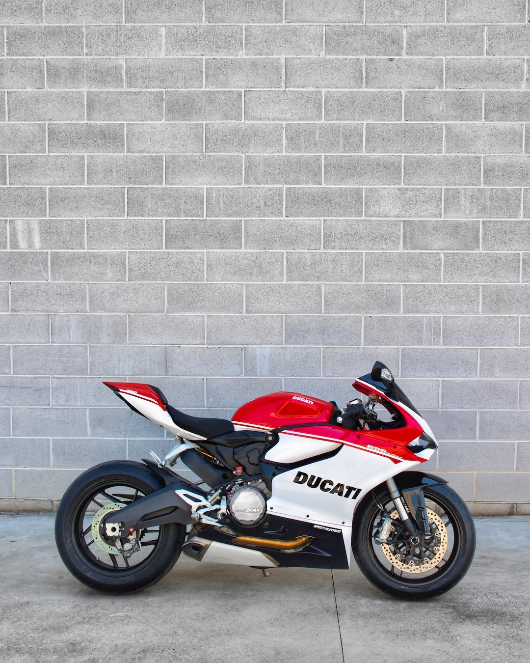red and black sports bike parked beside white brick wall