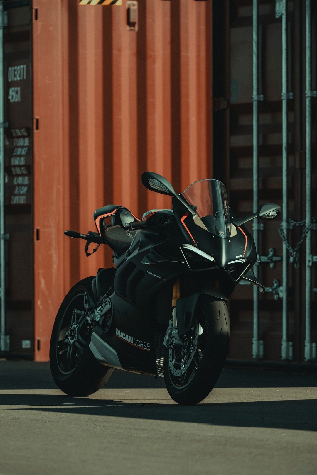a black motorcycle parked in front of a shipping container