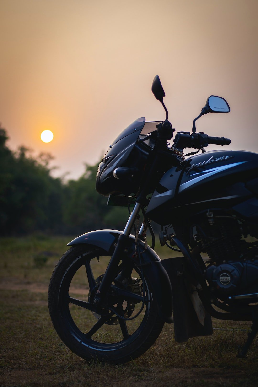 a motorcycle parked in a field at sunset