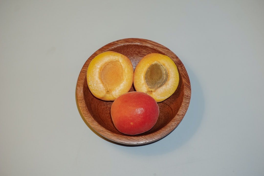 a wooden bowl filled with fruit on top of a table