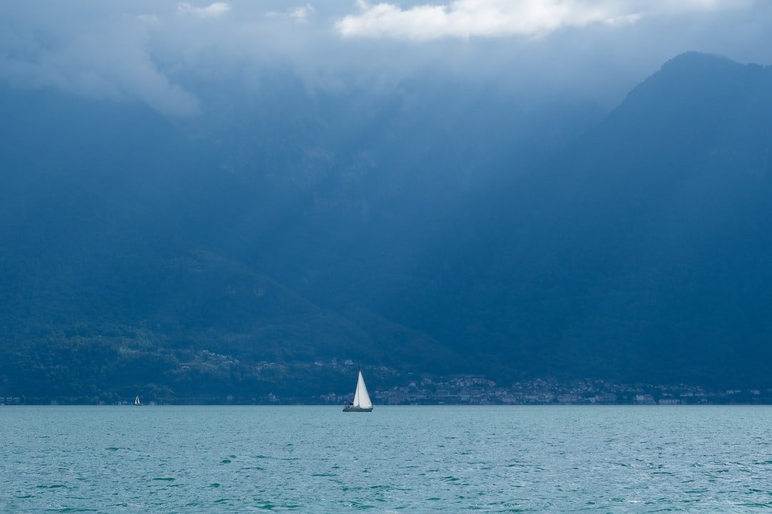 a sailboat in a large body of water with mountains in the background