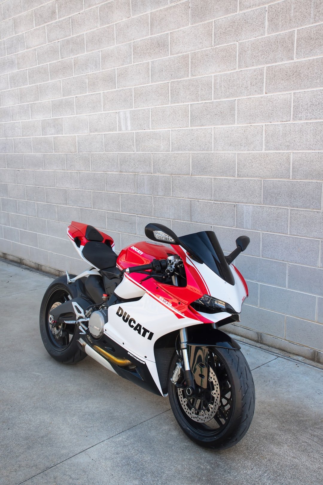 red and white honda sports bike parked beside white wall