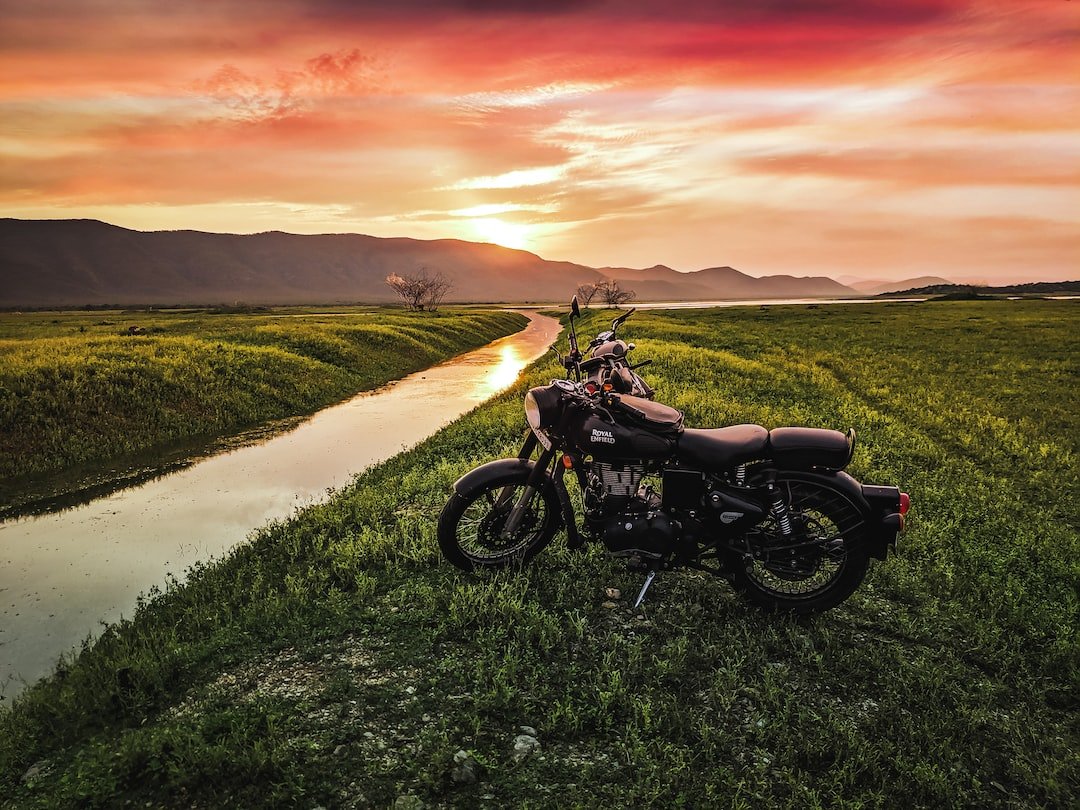 black motorcycle on green grass field during sunset